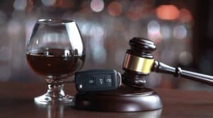 Glass of alcohol, car key, and judge's gavel on a table, symbolizing legal consequences of drunk driving.