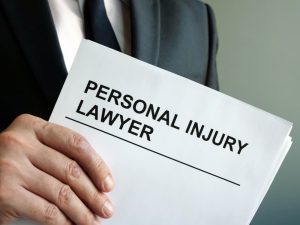 Person in a suit holding a document labeled "Personal Injury Lawyer," symbolizing legal services for accident or injury cases.