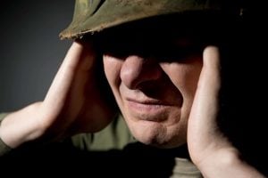soldier with hands over their ears