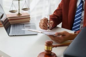 Lawyer reviewing documents with scales, gavel, and laptop, emphasizing statute of limitations in claims.